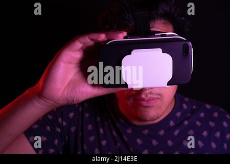 Young latin man using Virtual Reality VR Headset 3D Glasses. Dark backdrop. Low key. Stock Photo