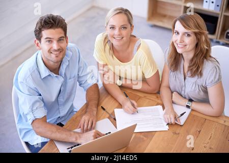 Doing what we do best. High angle shot of three young businesspeople sitting at a table. Stock Photo