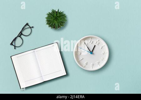 Office template. Eyeglasses, notepad, clock and succulent on the mint color background. Flat lay. Concept of education. Stock Photo