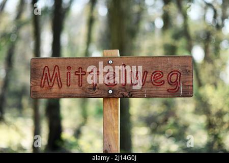 Wooden roadsign saying 'Mittelweg' ('middle ground' in English) in German Stock Photo