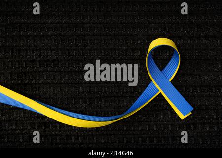 Blue and yellow ribbon for Ukraine on black grill cloth texture Stock Photo