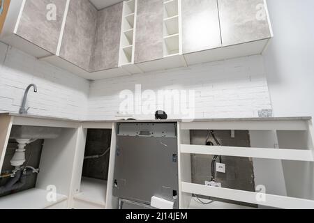 Installation hoses for dishwasher machine domestic connection plumbing pipes in kitchen Stock Photo