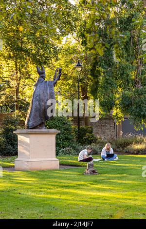 The statue of Bishop Henry Wardlaw watching over two female students studying in St Marys College Quadrangle, University of St Andrews, Fife, Scotland Stock Photo