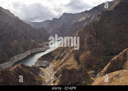 Presa del Parralillo water reservoir in the valley between arid volcanic mountains of Tejeda, northwest of Gran Canaria Canary Islands Spain. Stock Photo