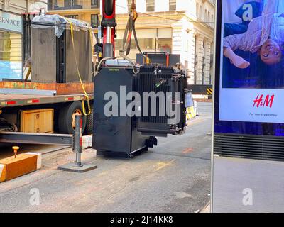 New York, NY, USA - March 20, 2022: A new electric transformer being lowered from a truck to sidewalk to replace an older transformer under the street Stock Photo