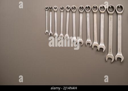 Many wrenches. Grey background. Set of wrenches in different sizes on grey background. Close up. Stock Photo