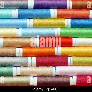 macro shot of rows of spools of multicolored sewing thread, laid alternately, with an offset. photo square Stock Photo