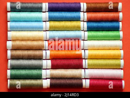 rows of spools of multicolored sewing threads are located throughout the photo Stock Photo