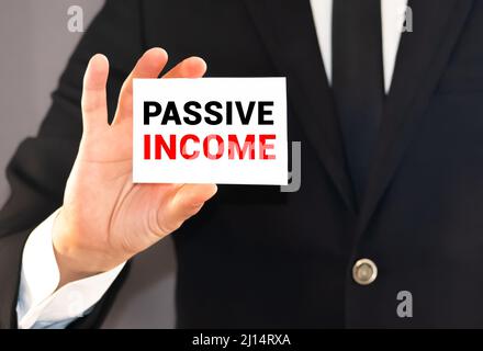 Businessman holding or showing card with text passive income Stock Photo