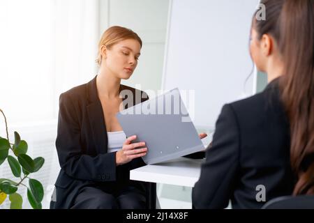 Job interview. Business, career and placement concept. Young blonde woman holding resume, while sitting in front of candidate during corporate meeting Stock Photo