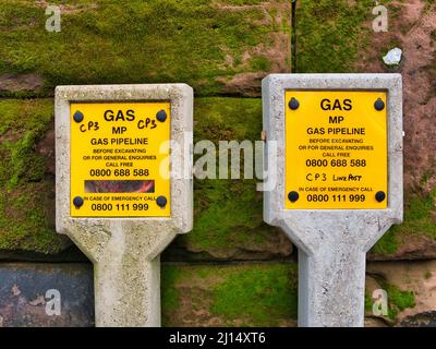 Yellow signs on concrete posts warn of Medium Pressure (MP) gas pipelines in an urban area in the north west UK. Stock Photo