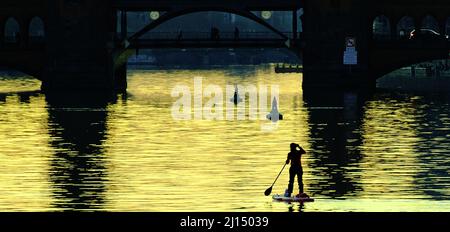 Berlin, Germany. 22nd Mar, 2022. A stand-up paddler is out in the evening on the Spree not far from the Oberbaumbrücke. Credit: Paul Zinken/dpa/Alamy Live News Stock Photo