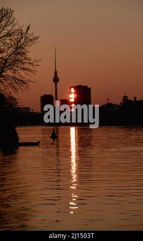 Berlin, Germany. 22nd Mar, 2022. The light of the setting sun is reflected in a glass facade not far from the TV tower. Credit: Paul Zinken/dpa/Alamy Live News Stock Photo