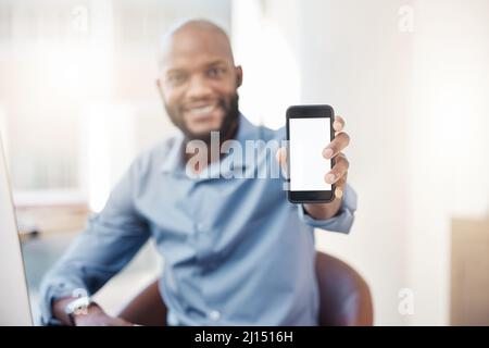 Let me get your details. Cropped portrait of a handsome young businessman holding his cellphone up to the camera while sitting in the office. Stock Photo