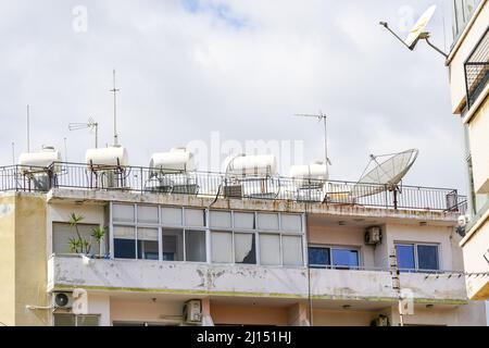 A lot of solar water heating systems with large water tanks and boilers on roof of house, also satellite dishes and antennas Stock Photo