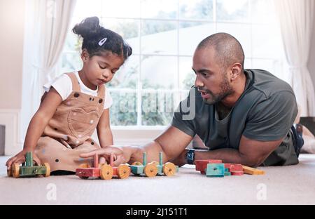 Lets build another choo-choo train. Shot of a father and his little daughter playing with wooden toys together at home. Stock Photo