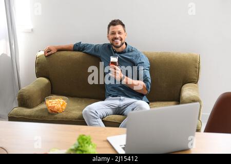 Handsome man drinking beer while watching sports at home Stock Photo
