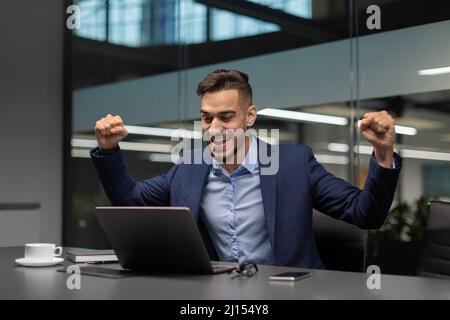 Emotional arabic businessman celebrating success at office Stock Photo