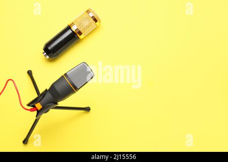 Modern microphones with stand on yellow background Stock Photo