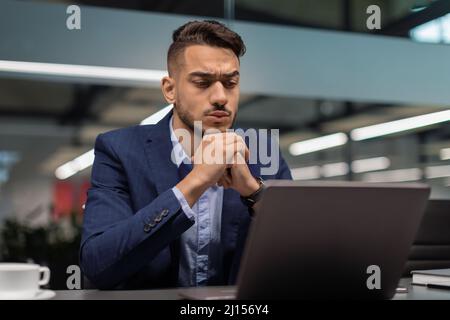 Closeup of pensive middle eastern businessman looking at notebook screen Stock Photo