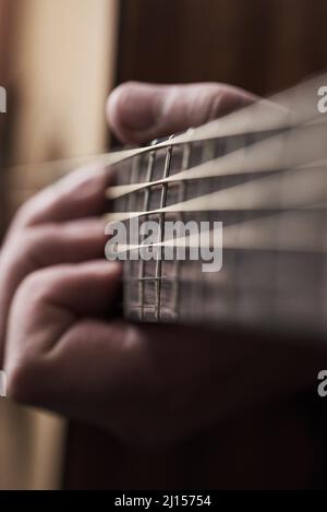 Sweet sounding strings. Cropped shot of an unrecognizable man playing an acoustic guitar at home. Stock Photo