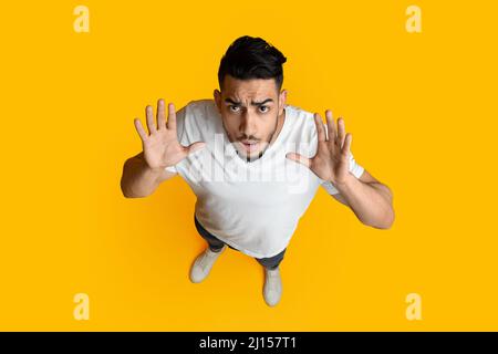Top view of confused middle eastern guy raising hands up Stock Photo