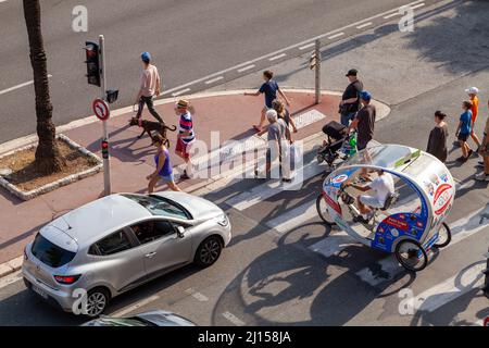 Nice, France - August 13, 2018: Cars, pedestrians and tourists trishaw bike are on the road on a sunny day