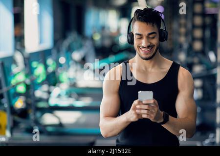 Happy Young Arab Man Messaging On Smartphone While Relaxing After Sport Workout Stock Photo
