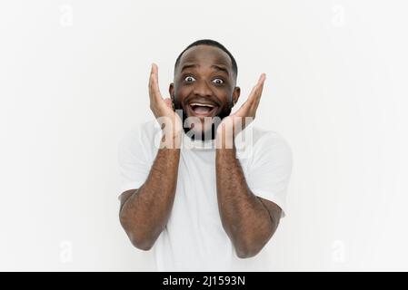 My God! Amazed african american man screaming excitedly and looking at camera on white background. A black young man gesticulates with his hands, expr Stock Photo