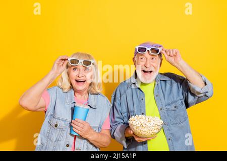 Photo of shocked girlfriend boyfriend dressed denim outfit enjoying pop corn watching movie isolated yellow color background Stock Photo