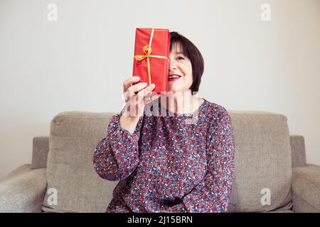 Grandmother plays with a present covering half of her face Stock Photo