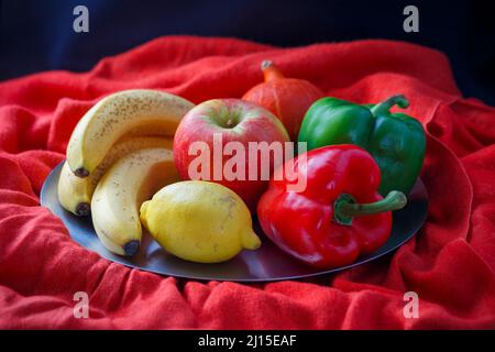 Still life of vegetables and fruits of various kinds on a plate on an arranged background. Stock Photo