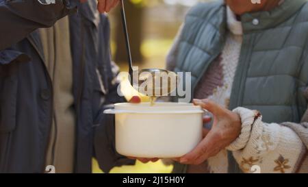 Senior Caucasian couple getting food nature background aged people wellbeing support concept focus on hands, container and ladle closeup selective focus . High quality photo Stock Photo