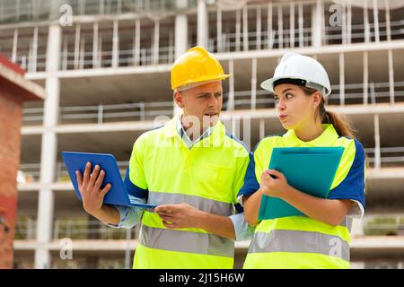 Two engineers are discussing an important project, holding a laptop and an estimate Stock Photo