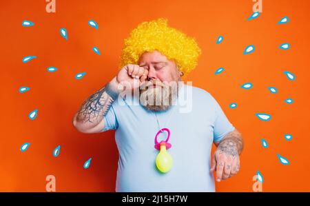 Funny man with wig act like a baby and cries for something Stock Photo