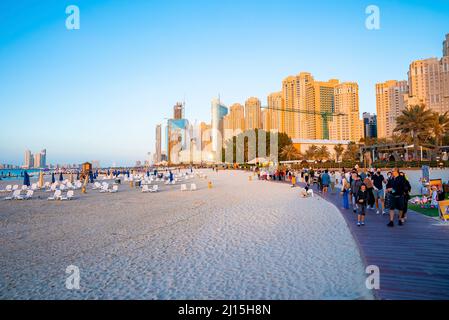Urban cityscape with tourists walking on footbrige over beach sand Stock Photo