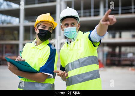 Civil engineers in masks checking work process Stock Photo