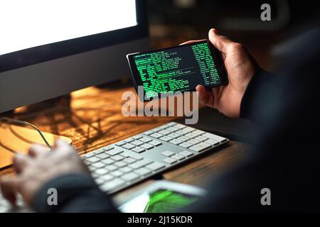 Secure your system before its too late. Cropped shot of an unidentifiable hacker cracking a computer code in the dark. Stock Photo
