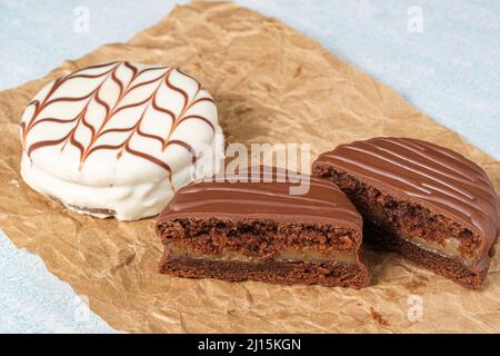 Brazilian honey cake cut in half, next to another with white chocolate frosting, on a brown paper. Stock Photo