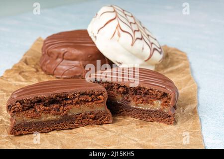 Closeup of a Brazilian honey cake cut in half, next to another one with white chocolate frosting, on a brown paper. Stock Photo