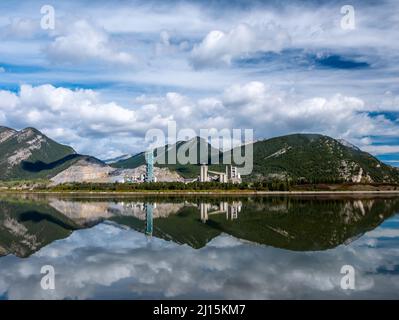 Lac Des Arcs, Alberta, Canada with a beautiful relfection and a cement plant in the background Stock Photo