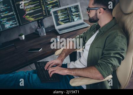 Photo of positive busy young guy dressed khaki shirt glasses writing data software modern gadget indoors workshop workstation Stock Photo