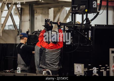 Industrial workers assembles agricultural harvester in workshop. Stock Photo