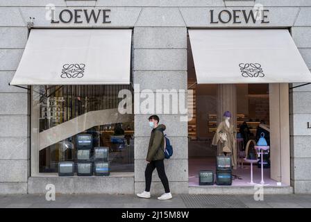 A pedestrian passes advertisements outside the Loewe SA luxury