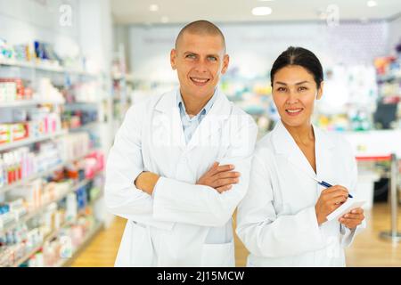 Two pharmacists in lab coats standing in drugstore Stock Photo