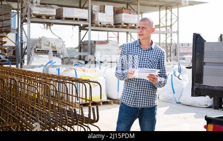 Man worker with papers collecting order at warehouse Stock Photo