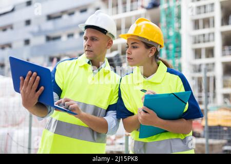 Two engineers are discussing an important project, holding a laptop and an estimate Stock Photo