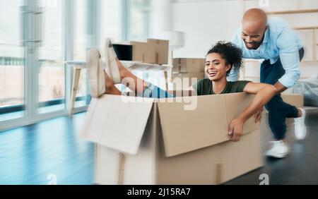This is our new adventure. Shot of a young couple having fun while moving house. Stock Photo