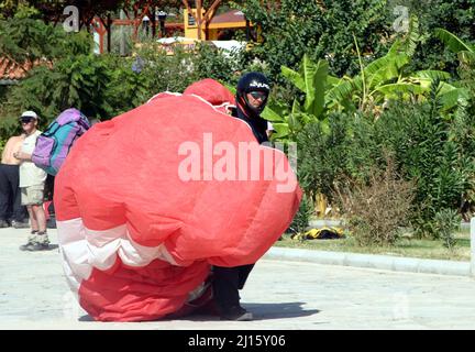 FETHIYE, TURKEY - OCTOBER 22: Paraglider carrying to parachute at Fethiye Beach, October 22, 2003 in Fethiye, Turkey. Every year many air sportsmen attend to Fethiye Air Festival. Stock Photo