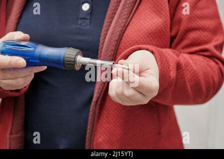 Woman in building materials store buys screwdriver with replaceable attachments Stock Photo